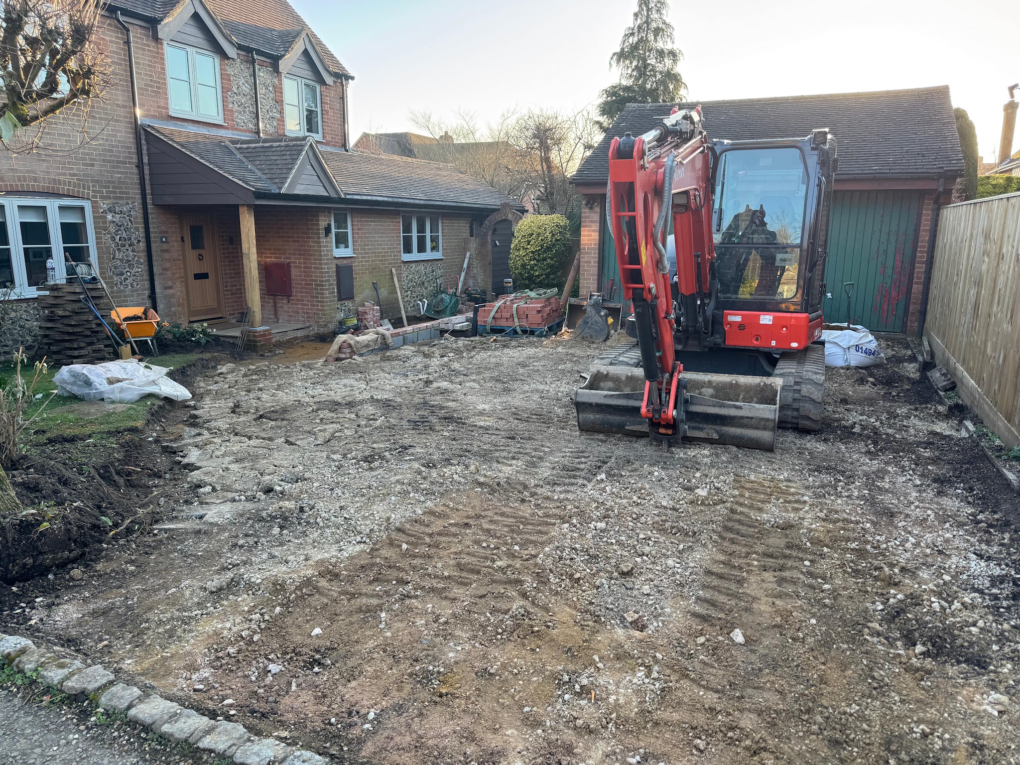 The old drive dug out, with a red mini digger on site