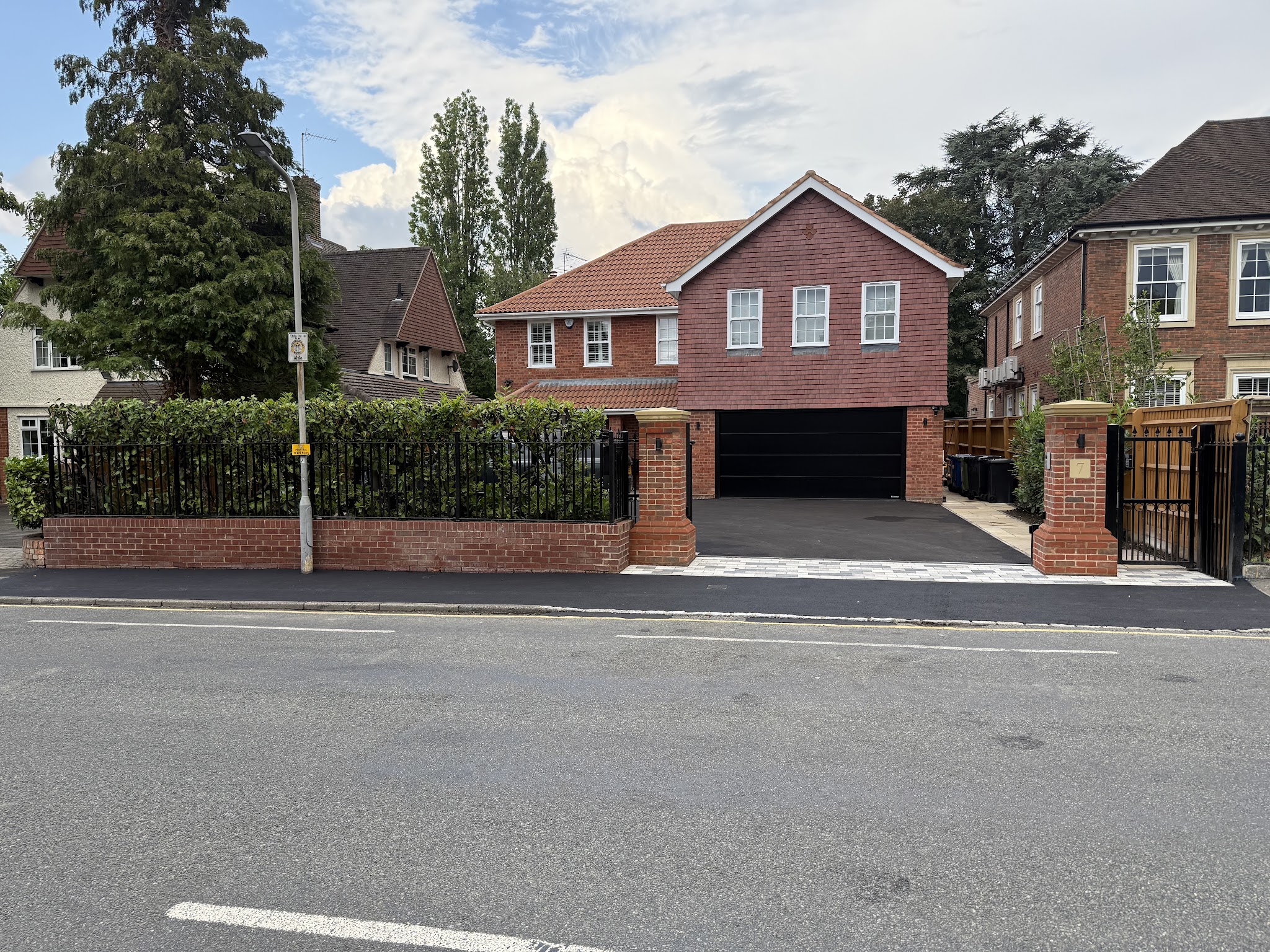 A large brick house with a new drive behind railings and brick piers