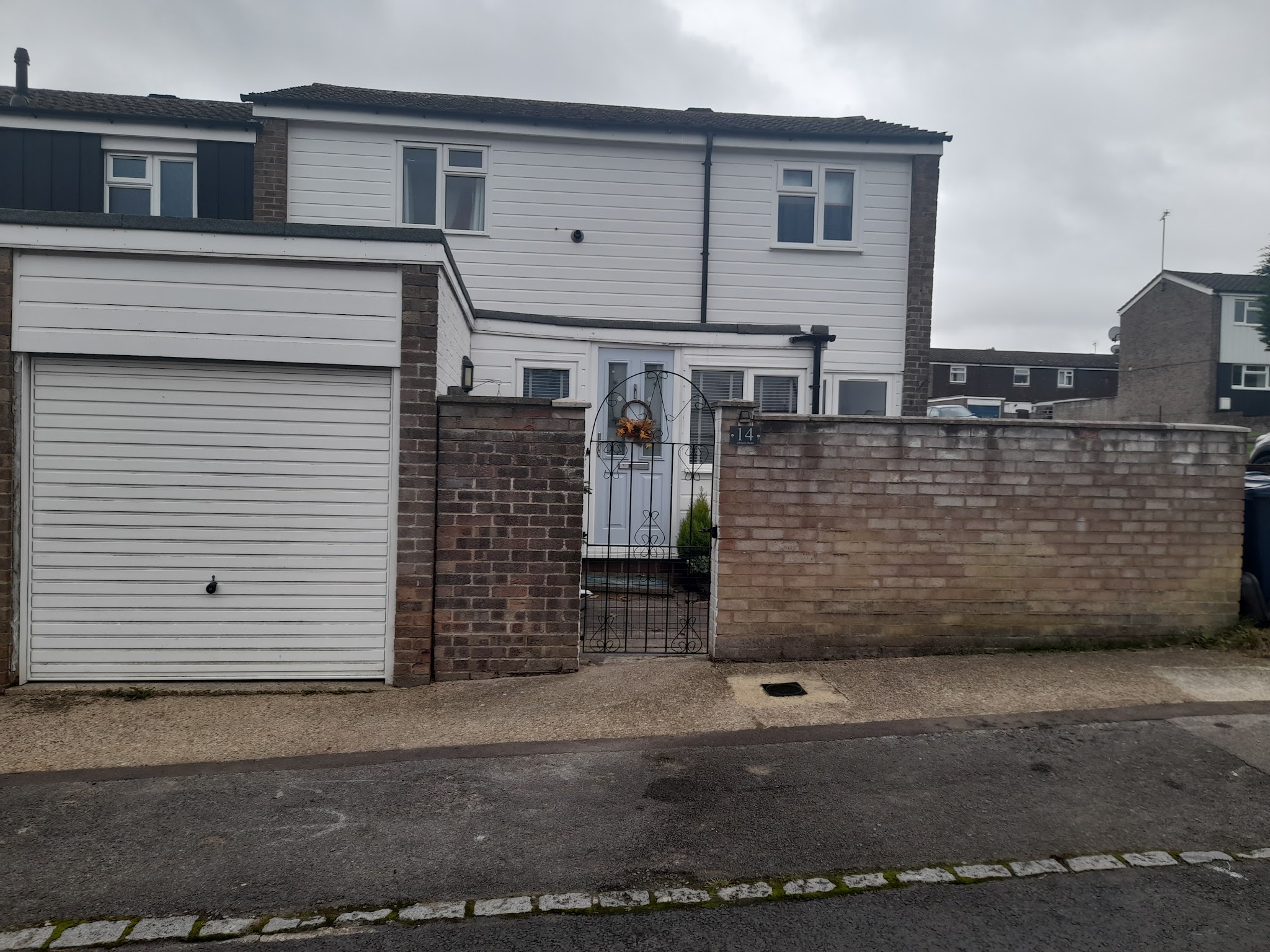 An old worn tarmac frontage in front of a white garage door