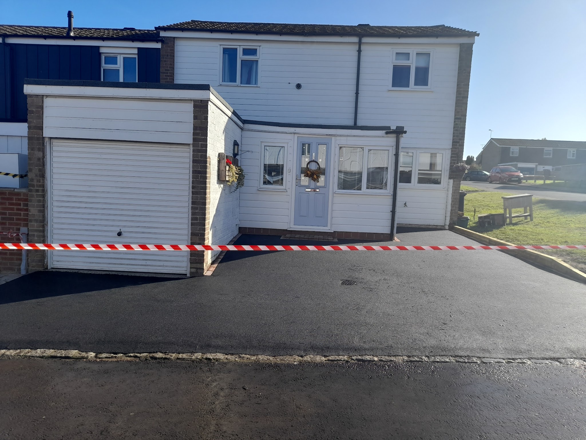 The same frontage with new black tarmac, taped off while it settles