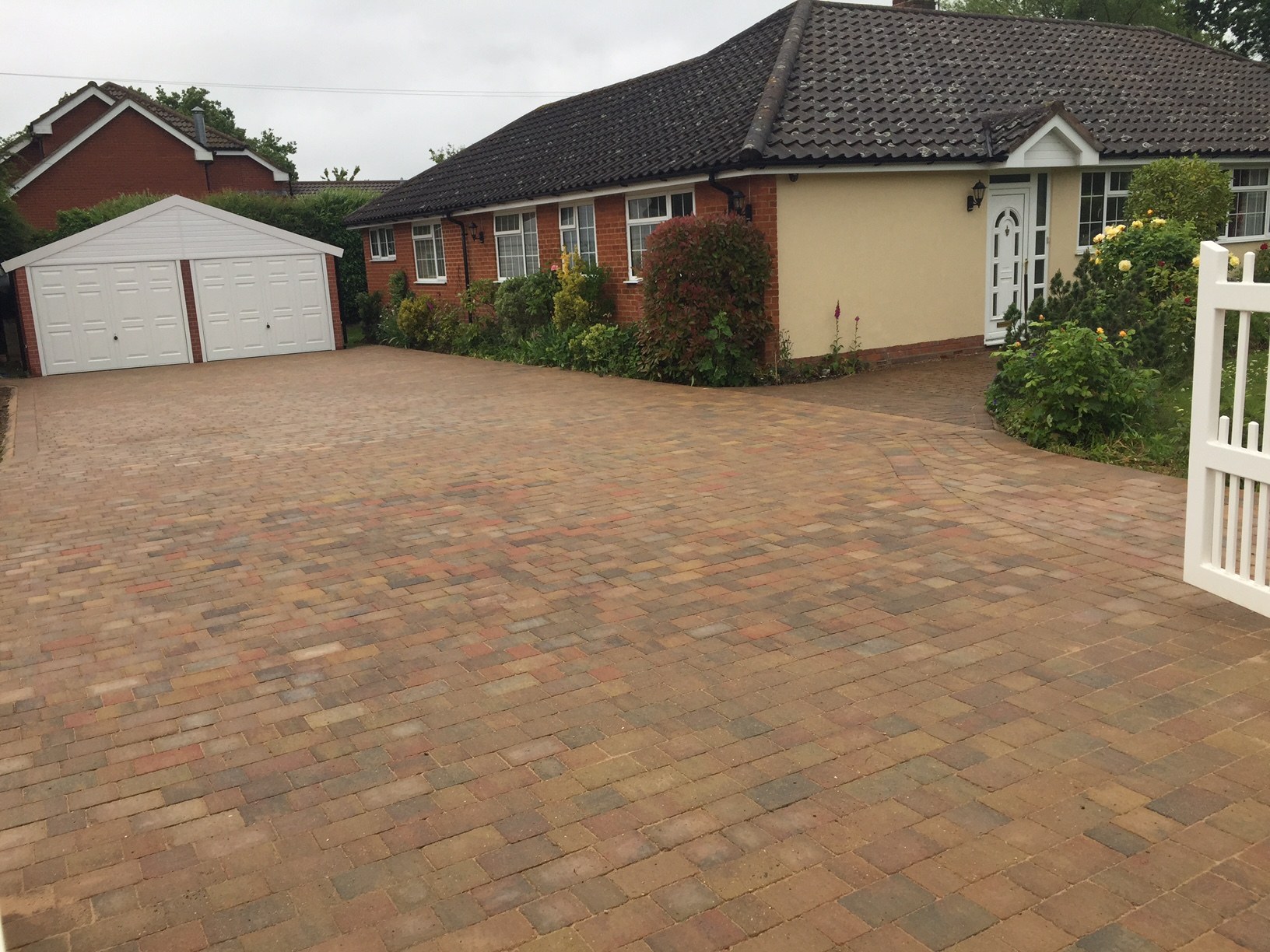 A finished buff block paved drive in front of a bungalow and double garage
