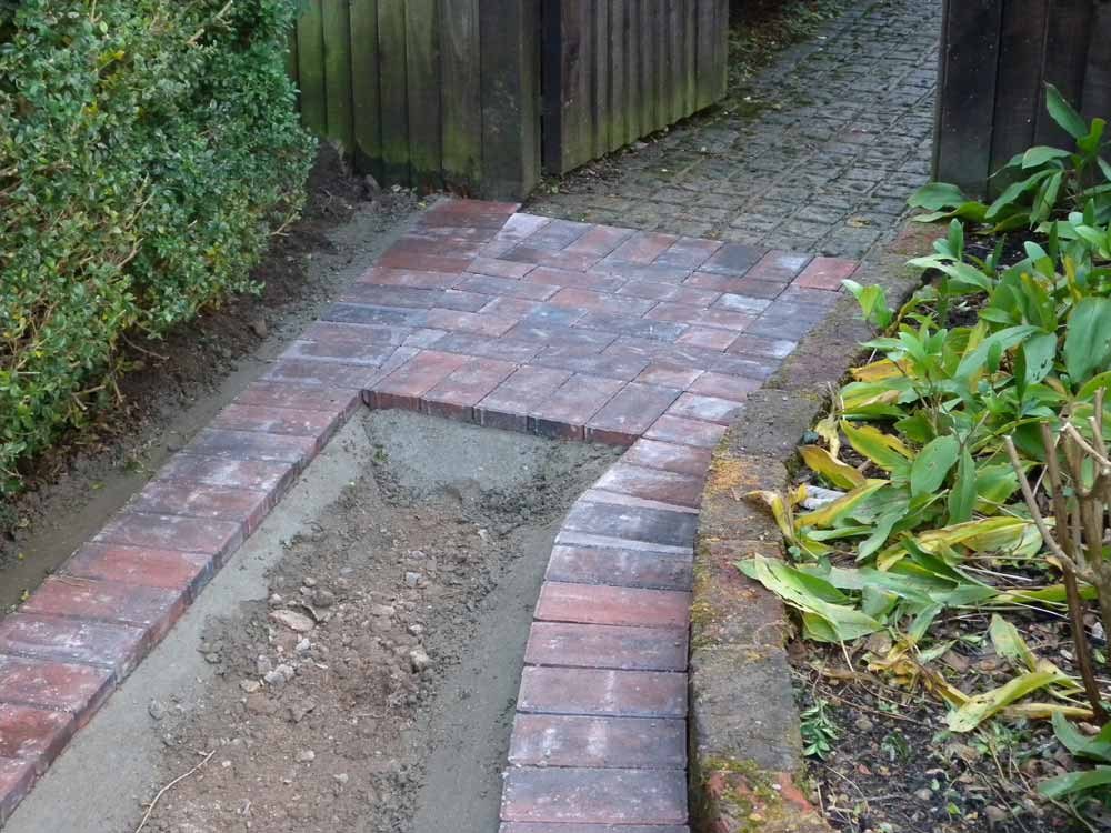 A brick paved path border taking shape between garden beds