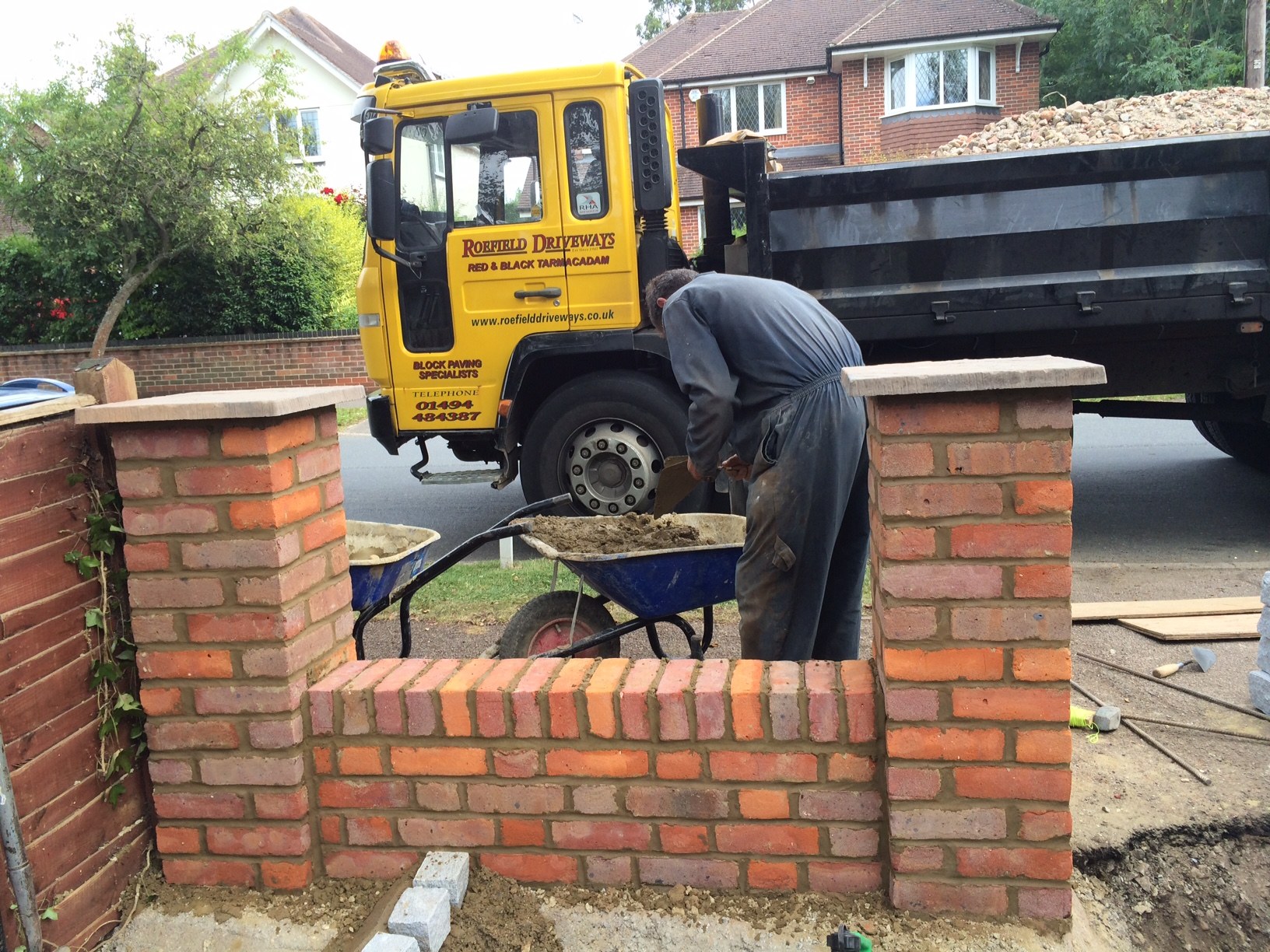 A brick pier being built, a yellow Roefield Driveways lorry behind