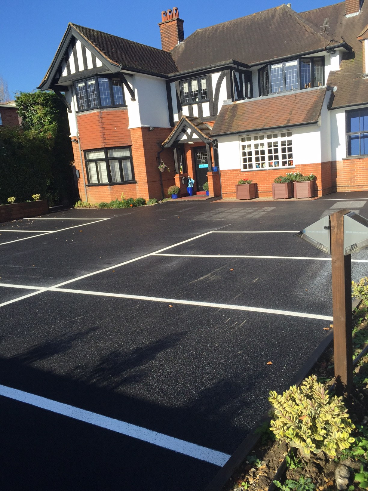 A lined car park in front of a Tudor style building