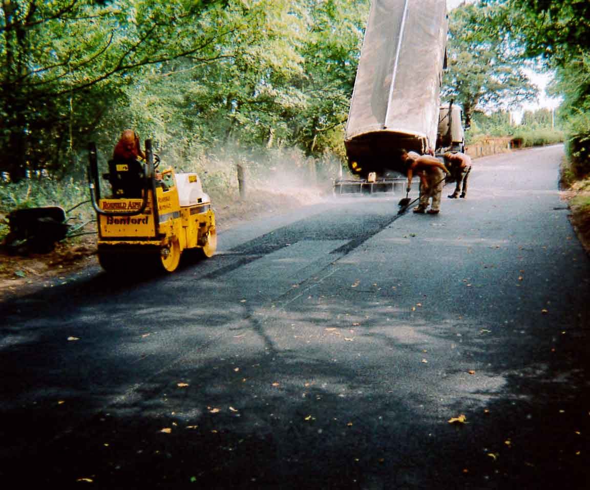 An estate road being surfaced with a roller and a tipper paver