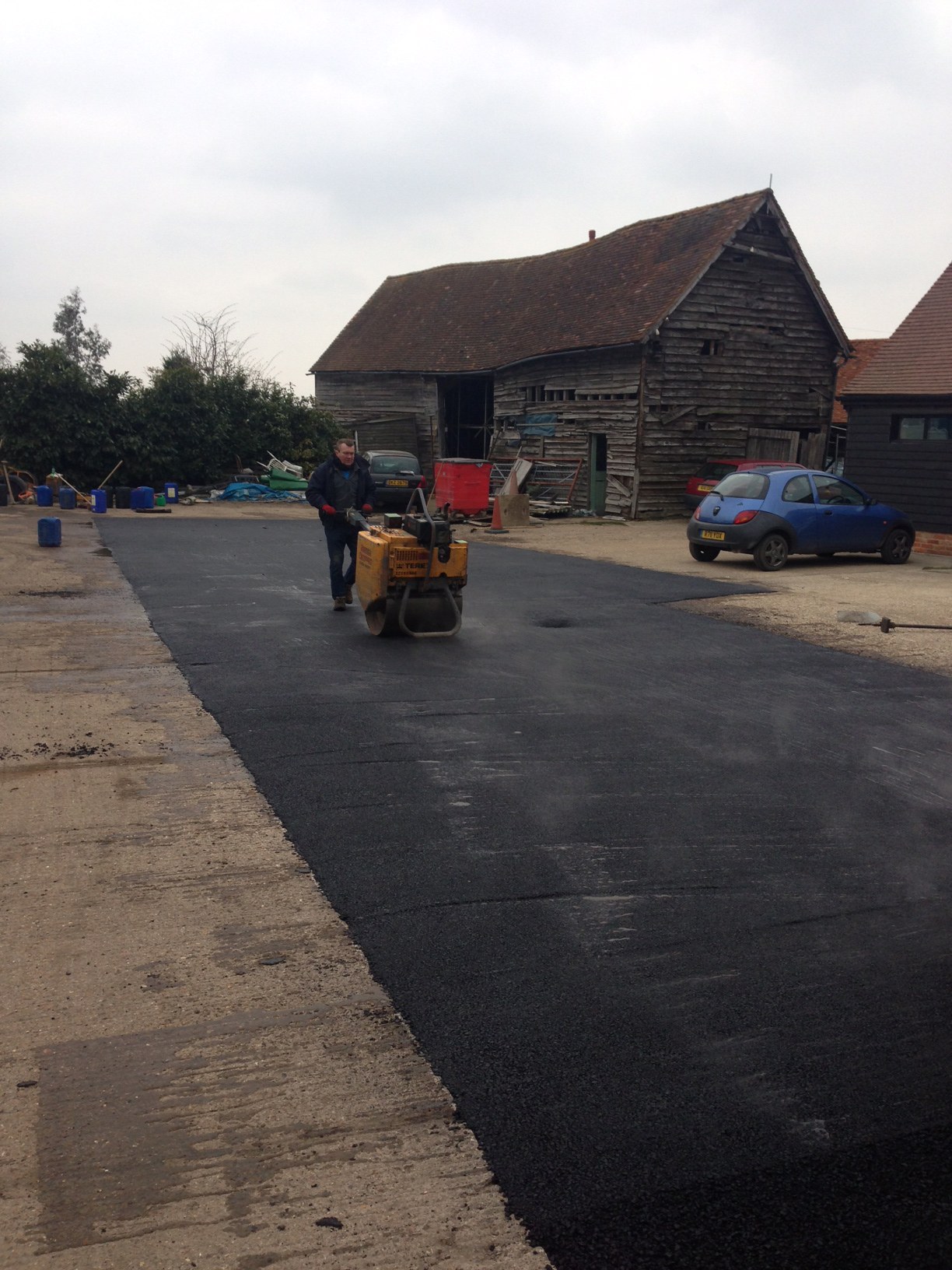 A farm yard beside an old timber barn being surfaced with fresh tarmac