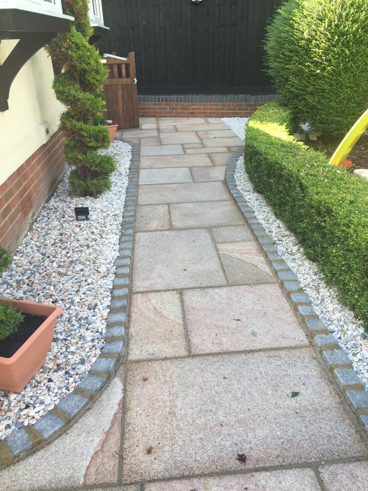 A sandstone path edged with grey setts between white stone borders