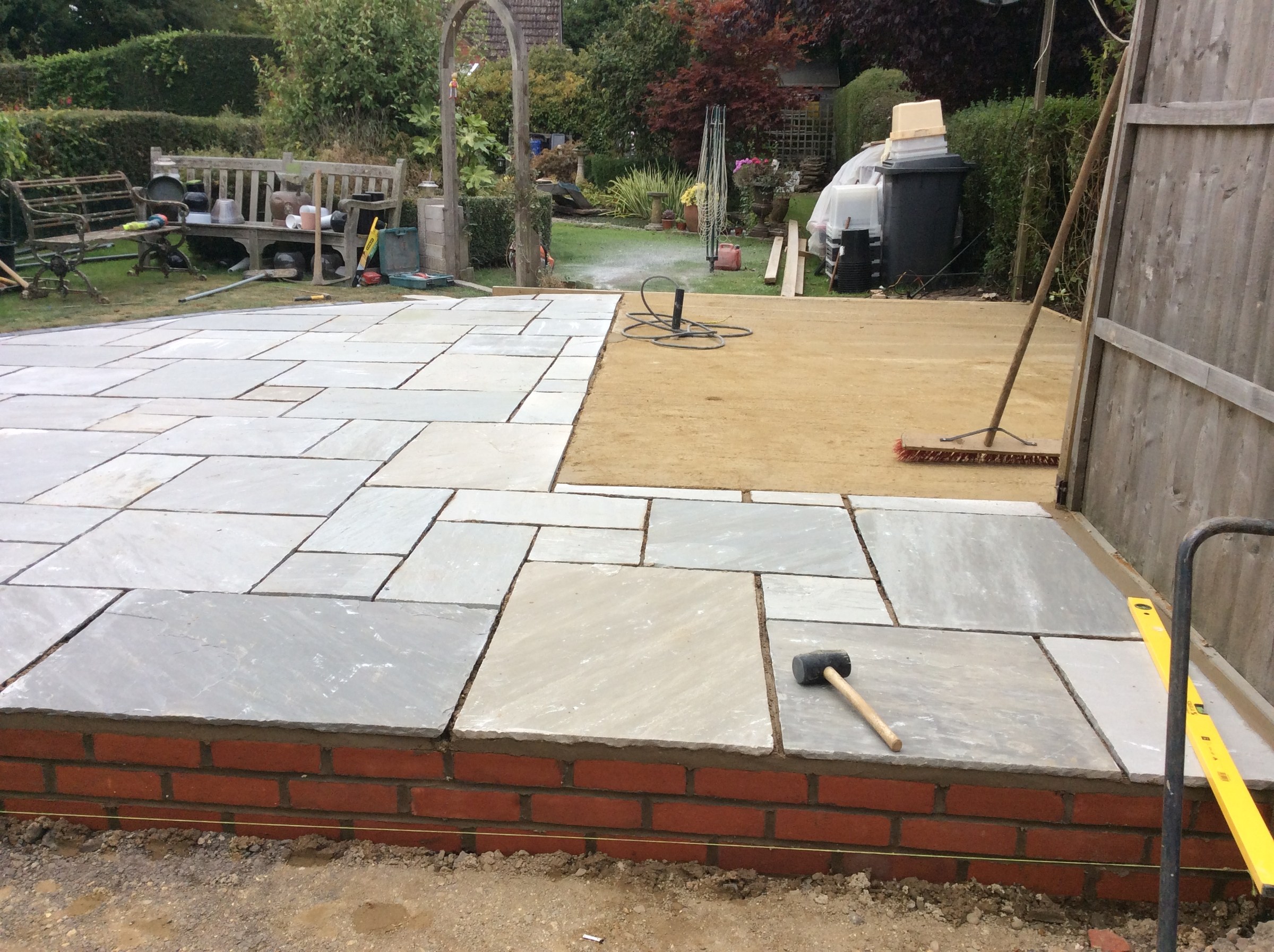 A sandstone patio with a brick step edge and the garden behind