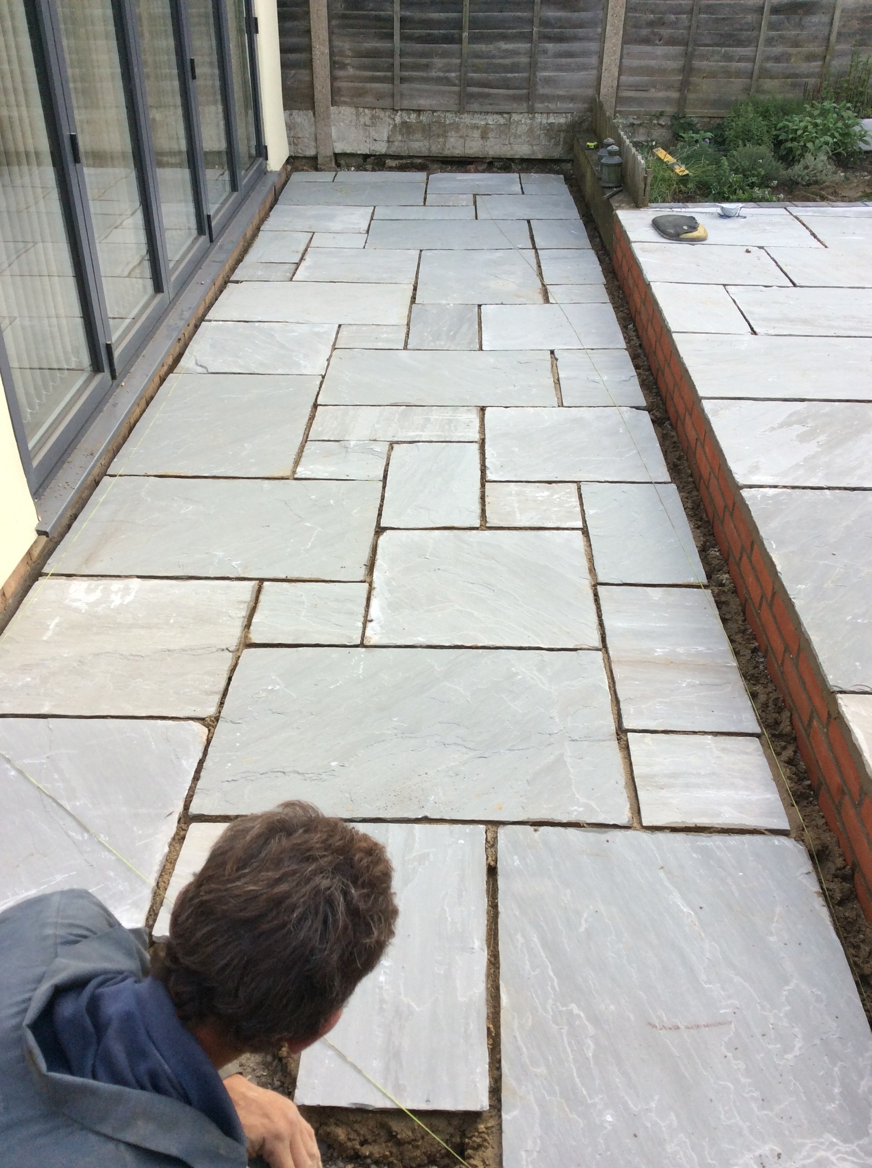 A long sandstone patio running along glazed doors