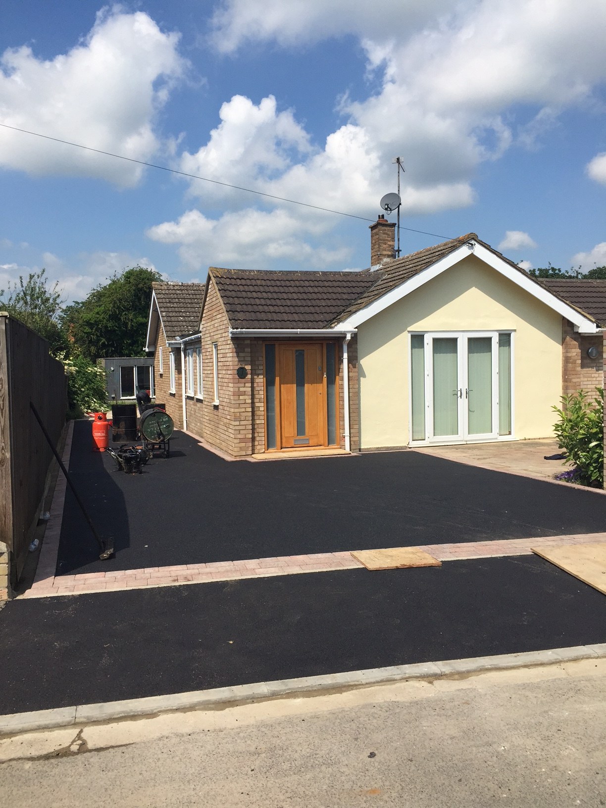 A new tarmac drive at a bungalow under a blue sky