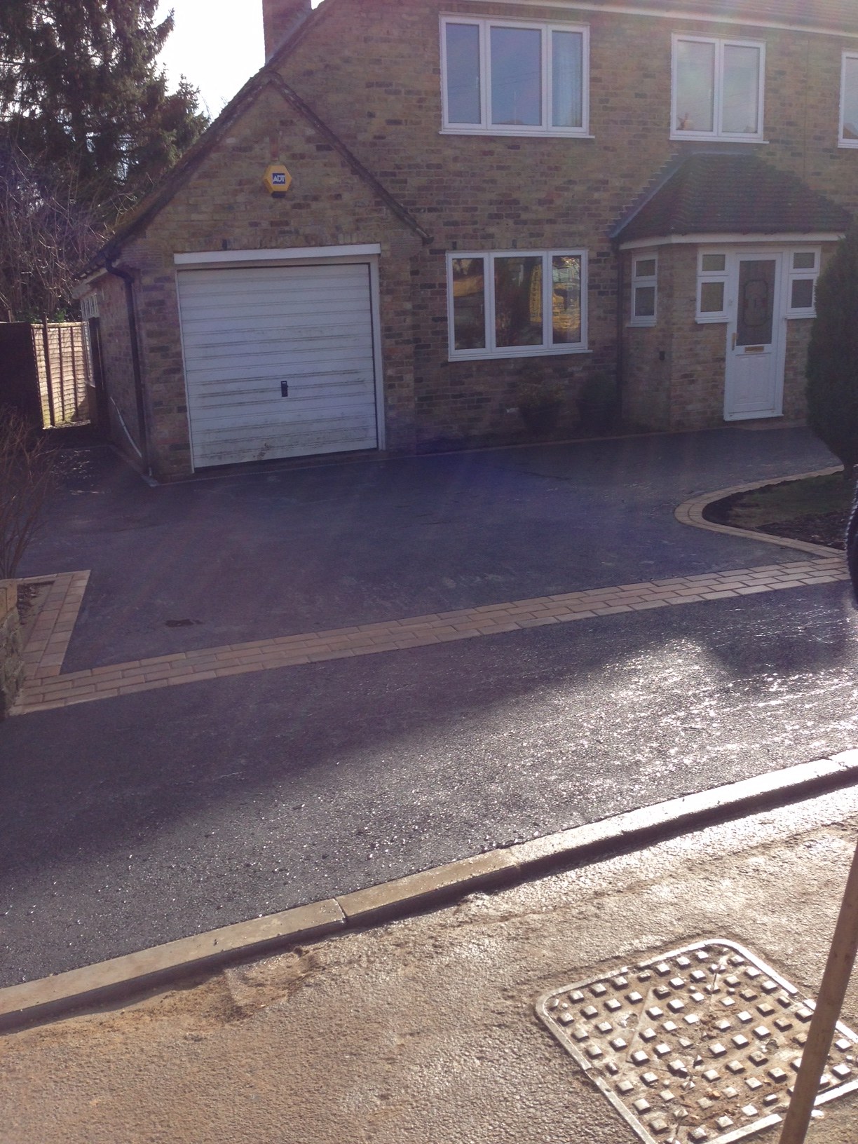A tarmac drive with block edging up to a garage