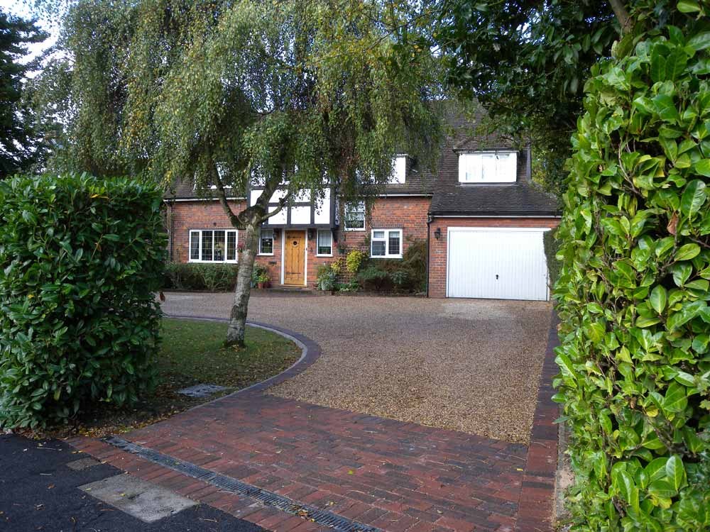 A finished drive with a brick paved apron between tall hedges